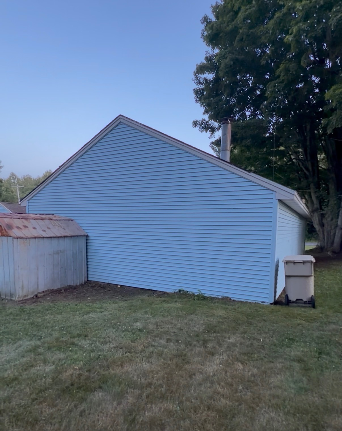 Green algae streaked siding soft washed back to clean blue — after